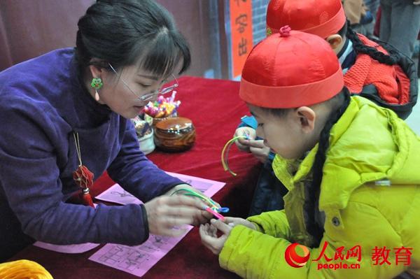 老師教小男孩編中國結(jié)。郭凱奇/攝。