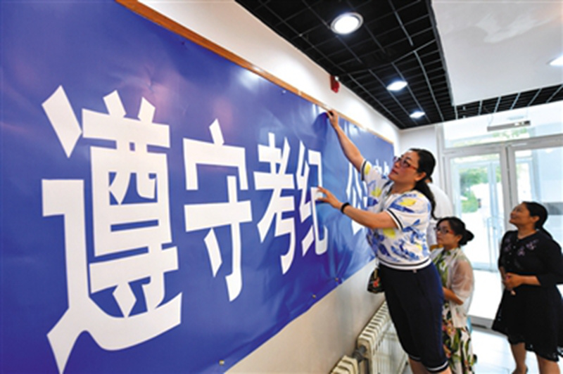 監(jiān)考老師在考場(chǎng)張貼考場(chǎng)紀(jì)律等標(biāo)語(yǔ)。李木易/攝