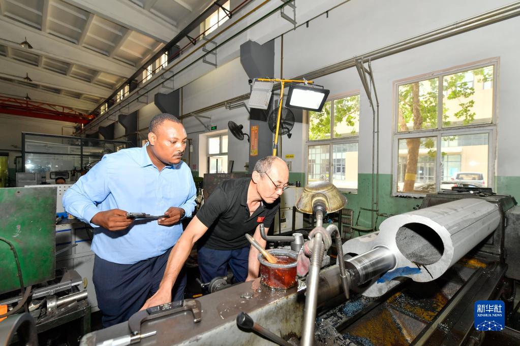 8月12日，在天津職業(yè)技術(shù)師范大學(xué)，韓士蘭（左）觀摩學(xué)校老師操作機(jī)床設(shè)施。新華社記者 孫凡越 攝
