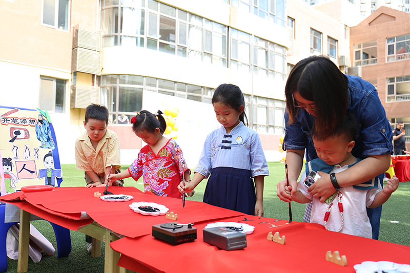 9月1日，北京市朝陽(yáng)區(qū)望京新城幼兒園以“開(kāi)筆啟智，禮潤(rùn)星寶”為主題的秋季開(kāi)學(xué)典禮拉開(kāi)帷幕。幼兒園開(kāi)展了朱砂啟智、擊鼓鳴智、開(kāi)筆啟智、盥洗禮等傳統(tǒng)文化互動(dòng)游戲，願(yuàn)知禮明禮、潛心向?qū)W的種子在孩子們的心中生根發(fā)芽。圖為老師帶小朋友開(kāi)筆啟智。北京市朝陽(yáng)區(qū)教委供圖