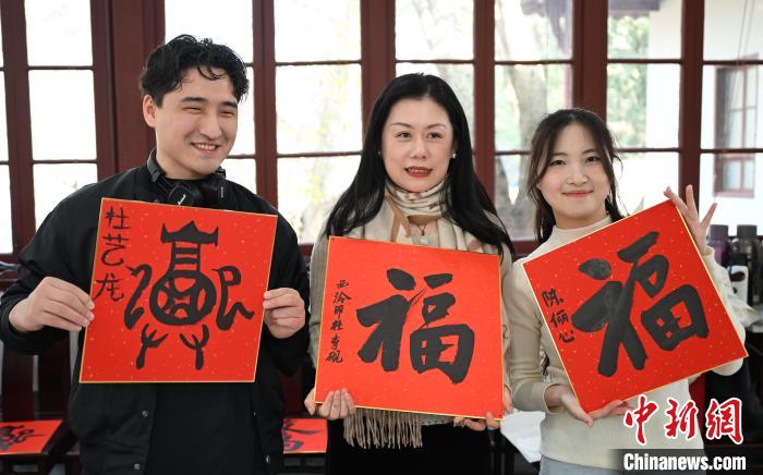 1月20日，外籍留學(xué)生和西泠印社社員李硯(中)展示各自創(chuàng)作的福貼。當(dāng)日，來(lái)自巴西、馬來(lái)西亞、加納、哈薩克斯坦的外籍留學(xué)生在浙江杭州西泠印社體驗(yàn)福貼、春聯(lián)和篆刻，感受古老的中國(guó)傳統(tǒng)文化。中新社記者 王剛 攝