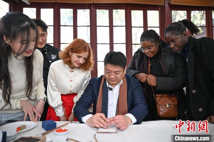1月20日，篆刻家王臻向外籍留學(xué)生展示篆刻印章。當(dāng)日，來(lái)自巴西、馬來(lái)西亞、加納、哈薩克斯坦的外籍留學(xué)生在浙江杭州西泠印社體驗(yàn)福貼、春聯(lián)和篆刻，感受古老的中國(guó)傳統(tǒng)文化。中新社記者 王剛 攝