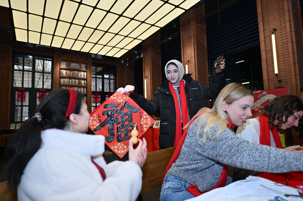 1月26日，留學(xué)生在天津意式風情區(qū)鐘書閣書店展示福字。