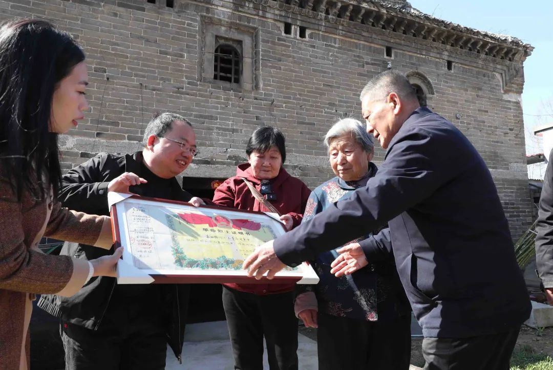 河南省許昌市建安區(qū)袁莊，曹明（左二）將修復(fù)好的革命烈士證明書(shū)交到袁松鶴烈士的家屬手中。