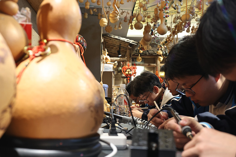 同學(xué)們用電烙筆在葫蘆上勾勒吉祥紋樣。校方供圖