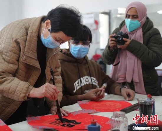 圖為書法愛好者指導(dǎo)外國留學(xué)生書寫福字?！〔芙ㄐ?攝