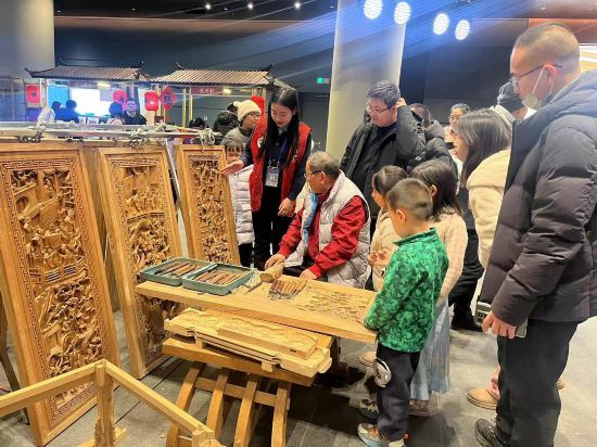 學(xué)生志愿者為觀眾講解老字號(hào)木雕技藝與文化故事