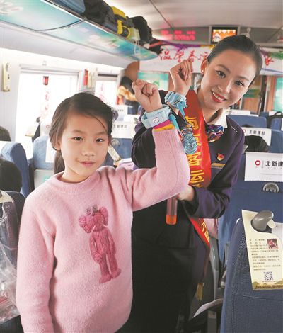 列車工作人員和小乘客展示防走失兒童專用手環(huán)。