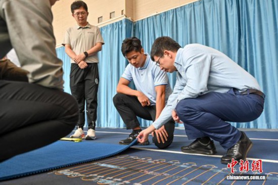 圖為蘇炳添在訓(xùn)練基地內(nèi)了解數(shù)字化跑道分析系統(tǒng)。中新社記者 陳驥旻 攝