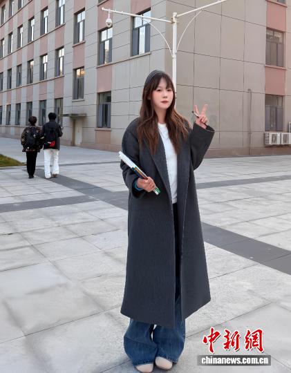 劉沫含在宿舍前拍照，她身著“雙十一”花200多元買的風(fēng)衣。 受訪者供圖